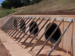 A view of a dam with four spillways set into a slope