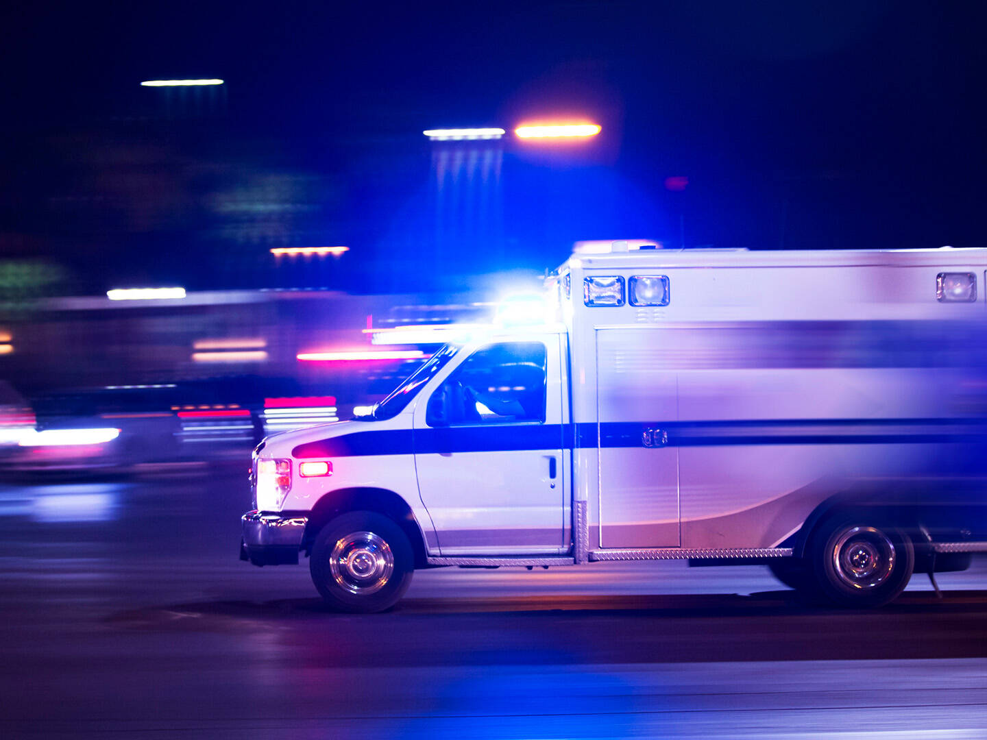 An ambulance speeding by on a dark road