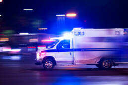 An ambulance speeding by on a dark road