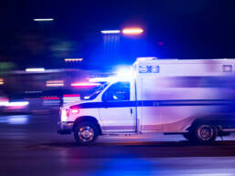 An ambulance speeding by on a dark road