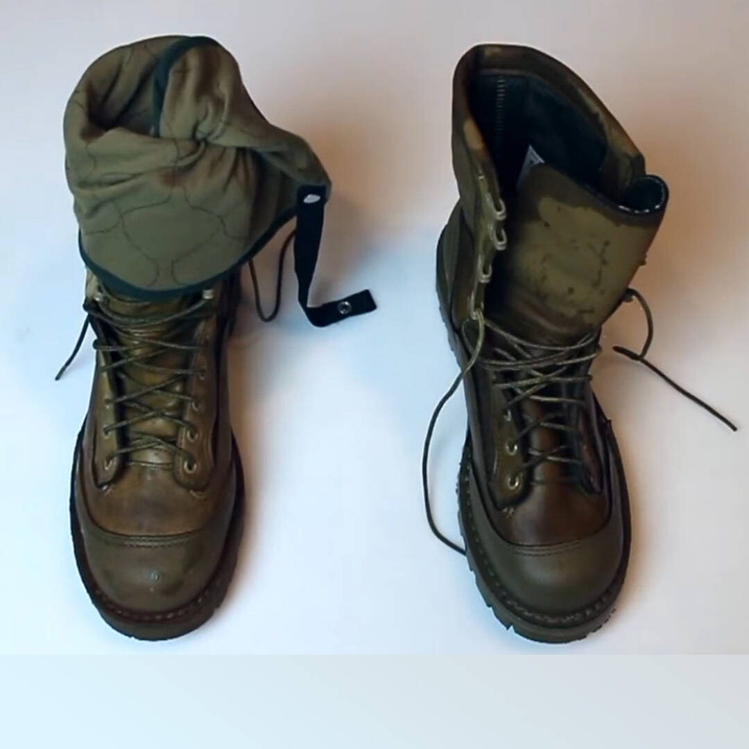 A pair of work boots, and a green fabric liner in one boot
