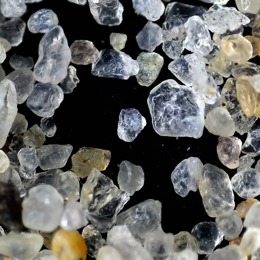 A microscopic view of grains of sand on a black background.