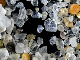 A microscopic view of grains of sand on a black background.