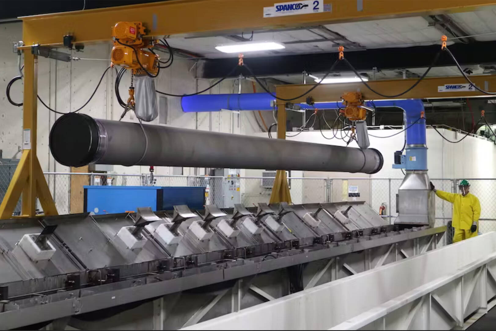 A large steel pipe suspended from the ceiling of a warehouse