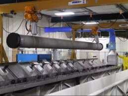 A large steel pipe suspended from the ceiling of a warehouse