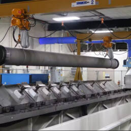A large steel pipe suspended from the ceiling of a warehouse
