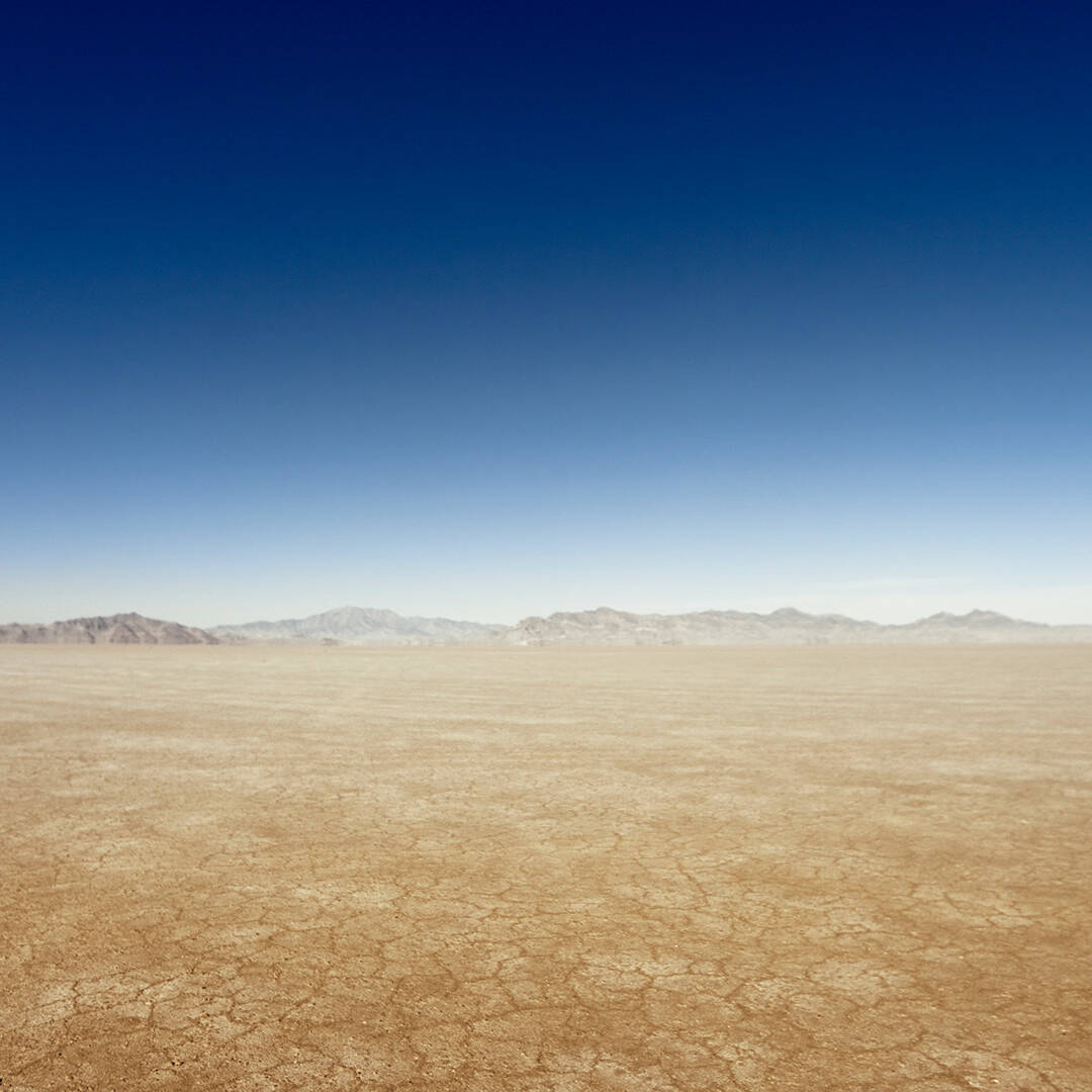 A vast desert landscape with mountains on the horizon