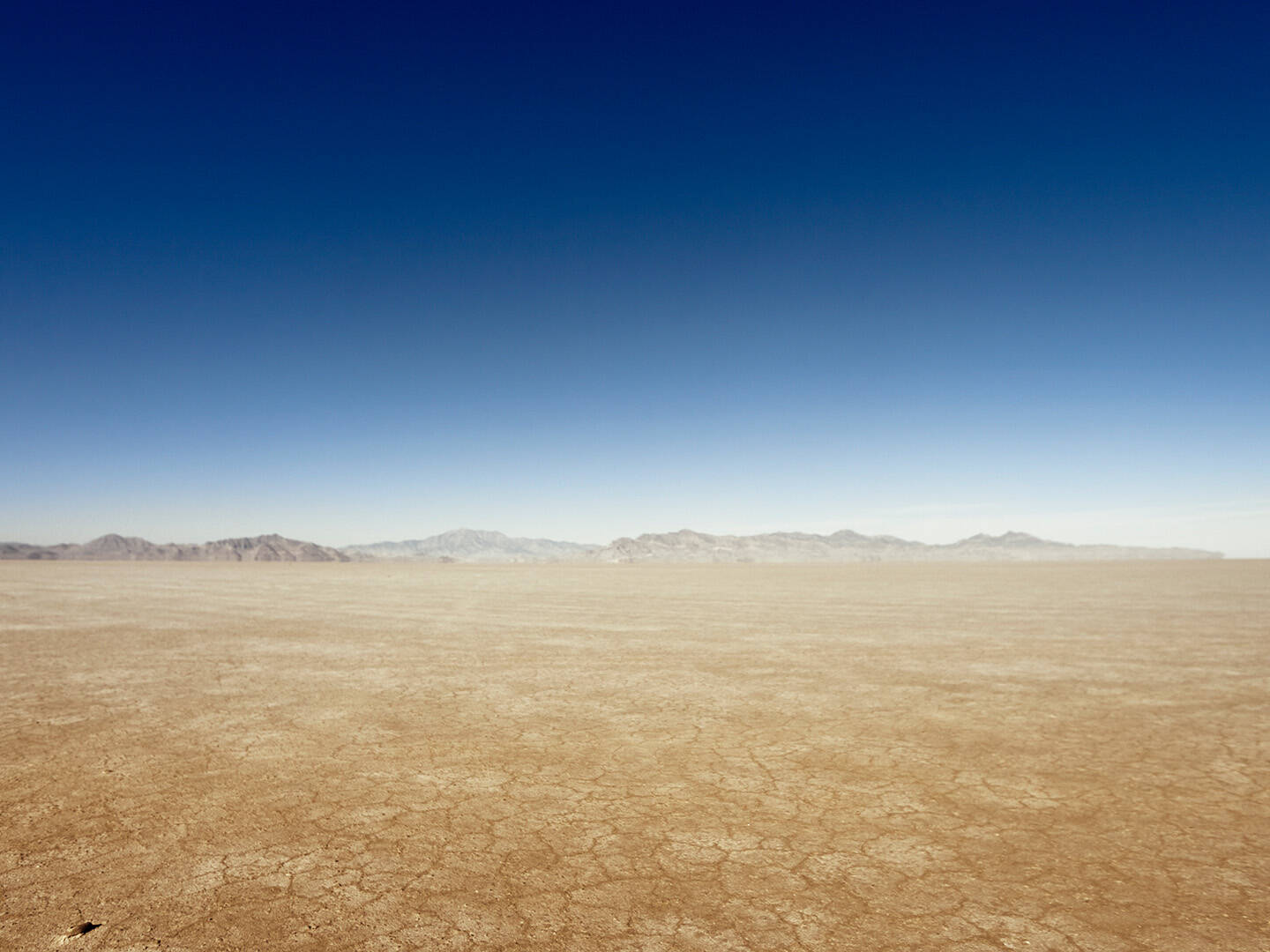 A vast desert landscape with mountains on the horizon