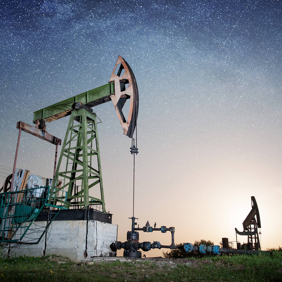 An onshore oil rig against a starry sky at dusk