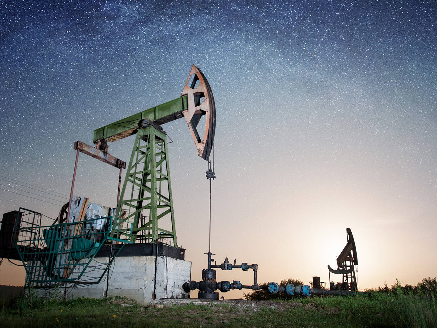 An onshore oil rig against a starry sky at dusk
