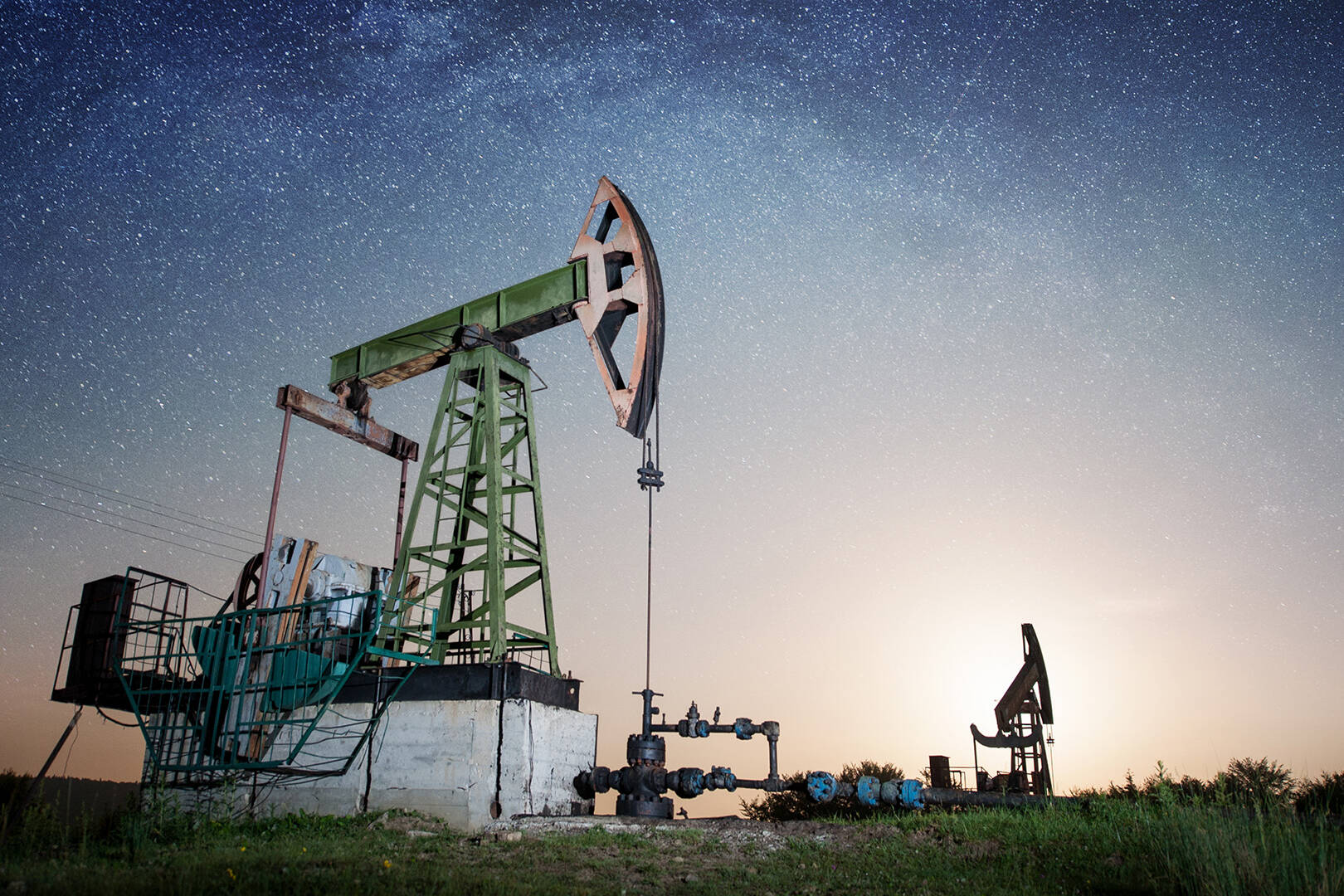 An onshore oil rig against a starry sky at dusk