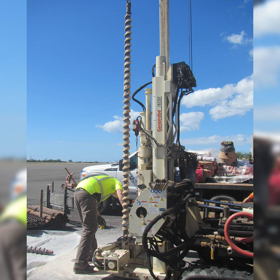 A worker adjusting drill equipment outside on pavement