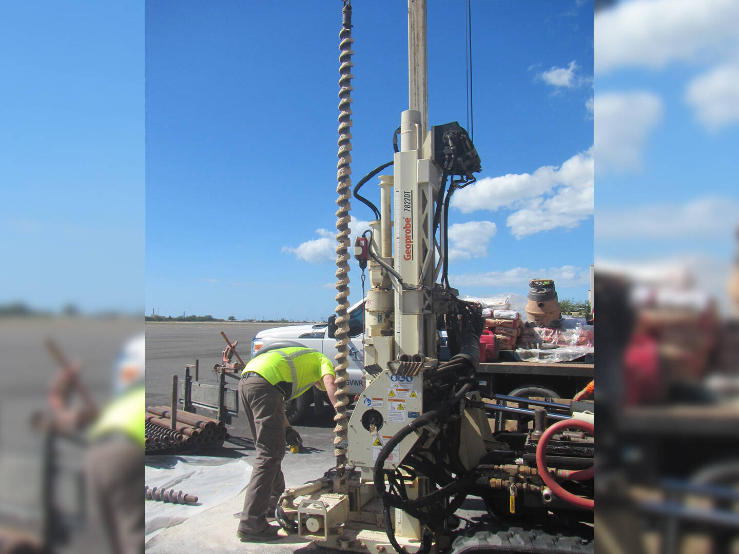 A worker adjusting drill equipment outside on pavement