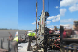 A worker adjusting drill equipment outside on pavement