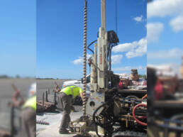 A worker adjusting drill equipment outside on pavement