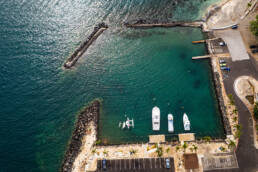 An ariel view of a harbor with small boats on dark blue water