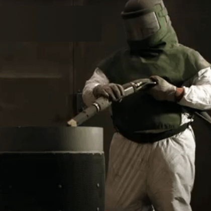 A worker using abrasive blasting