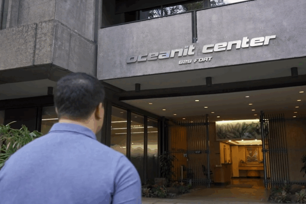 A photo of the back of a man's head while he walks into the Oceanit Center building