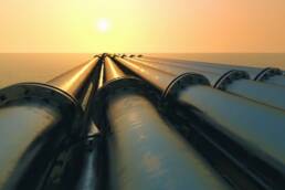 Pipelines leading to the horizon, where the sun sets over the ocean