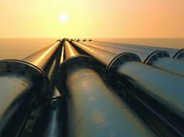 Pipelines leading to the horizon, where the sun sets over the ocean