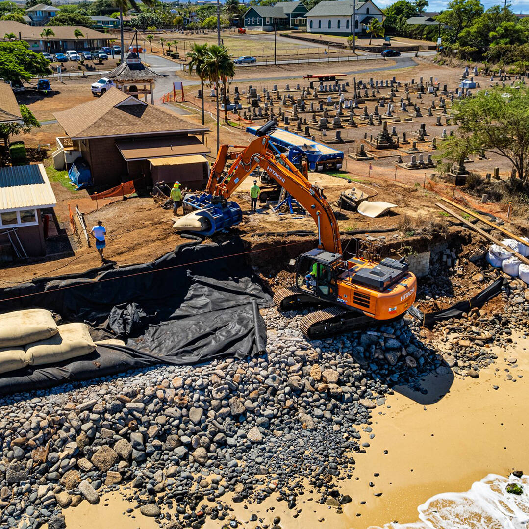 A construction loader placing sandbags on the shore of the Mantokuji temple