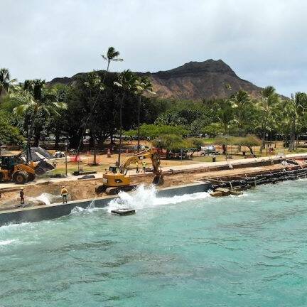Queen's Beach Waikiki seawall with a wave crashing into it