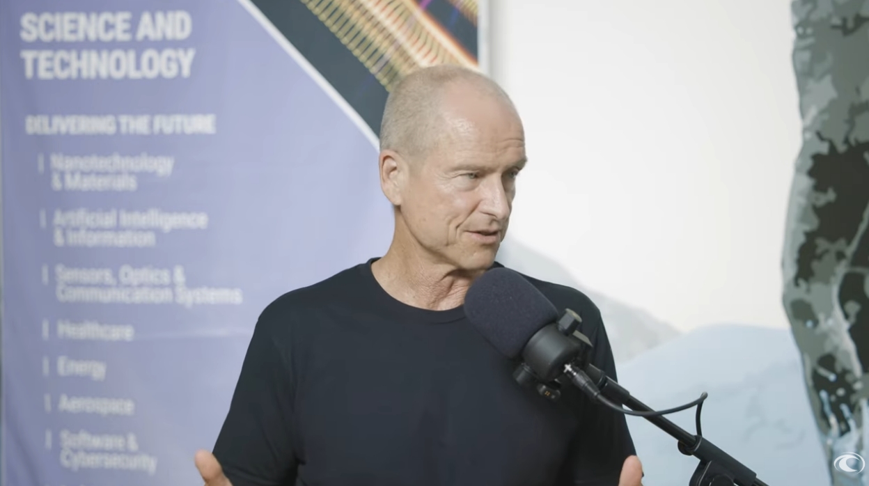 Patrick Sullivan speaking on a podcast microphone in the Oceanit office