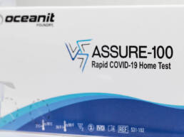 A white and blue box containing Oceanit's ASSURE-100 Rapid COVID-19 Home Test