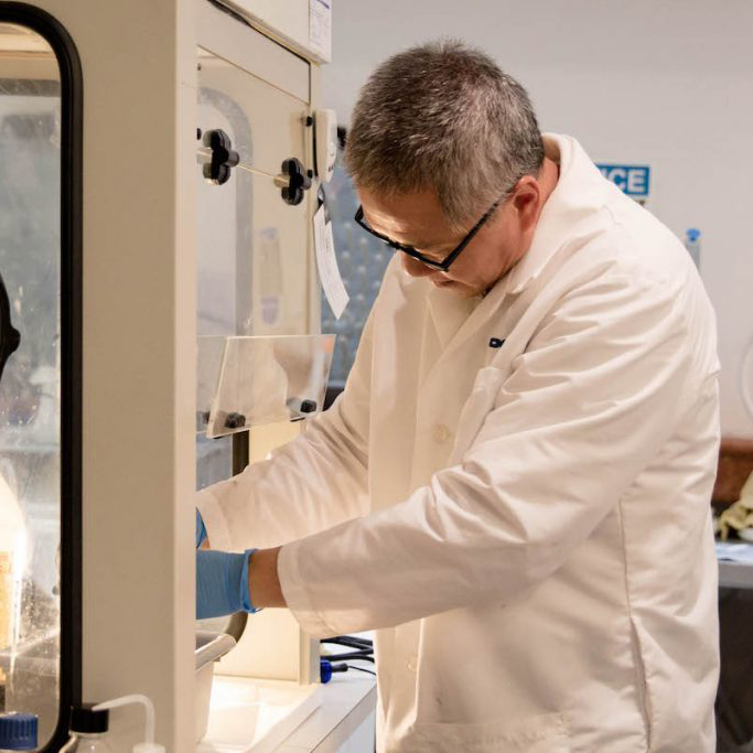A scientist preparing an object inside a large machine