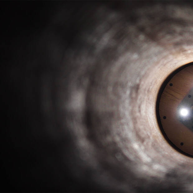 The inside of a pipeline, with lights illuminating the far end