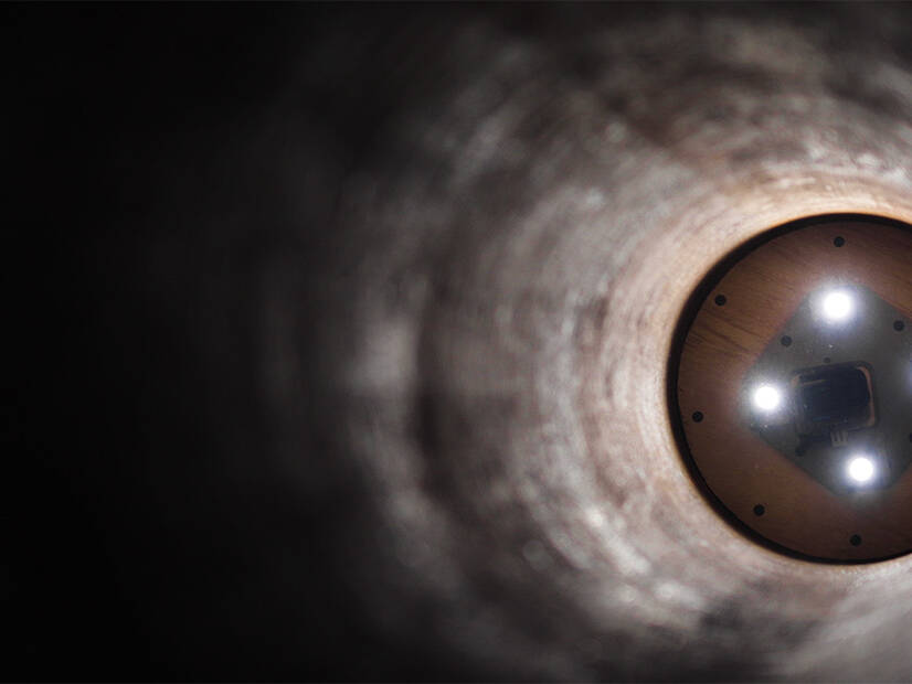 The inside of a pipeline, with lights illuminating the far end