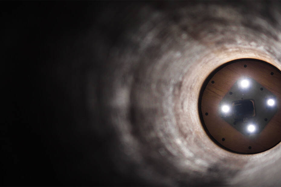 The inside of a pipeline, with lights illuminating the far end
