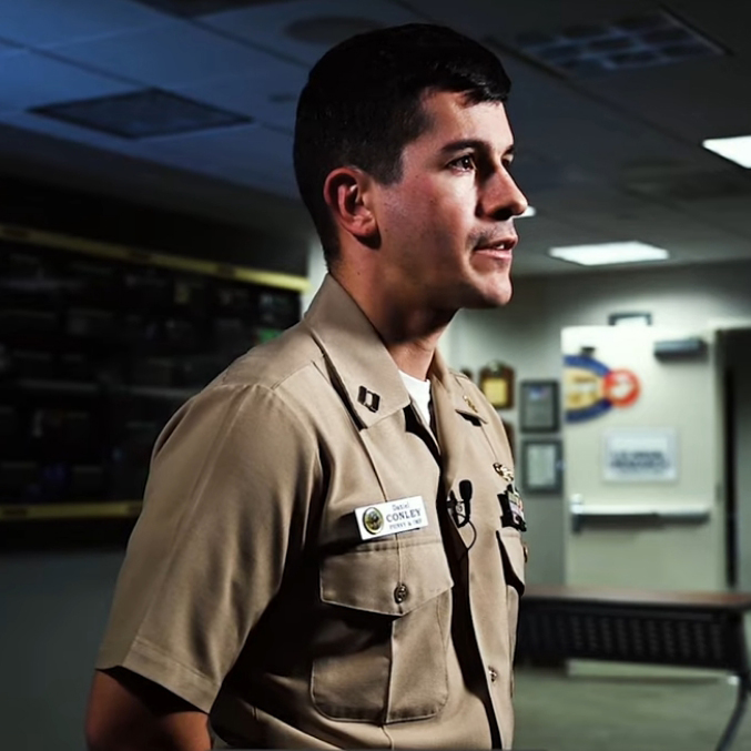 A profile view of Lt. Daniel Conley speaking to a camera in a dimly lit room