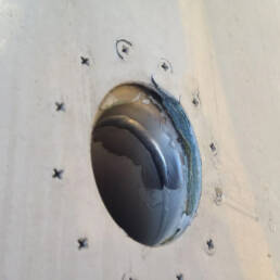 A close up of an exterior of aircraft with chipping paint and corroded exterior