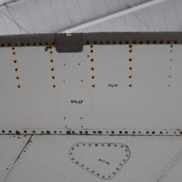 The underside of a plane wing with rusted screws