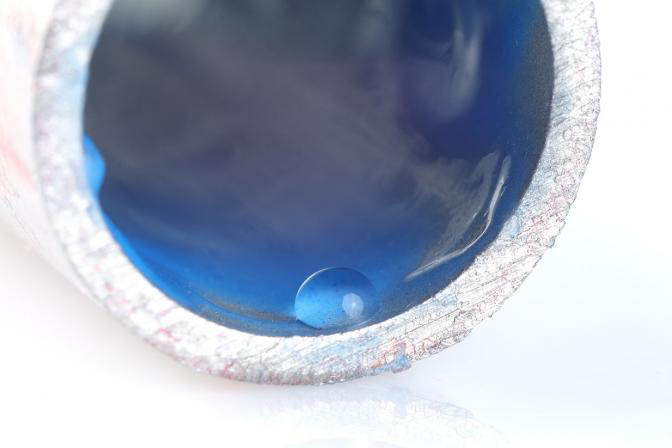 A pipe painted in a blue material with a water droplet beaded on the interior