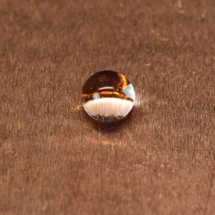 A bead of water on a textured brown surface