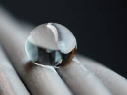 A close-up of a water droplet beaded on a twisted metal surface