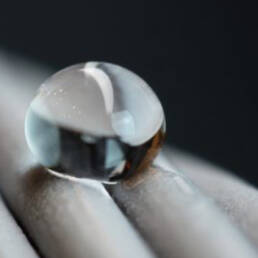 A close-up of a water droplet beaded on a twisted metal surface