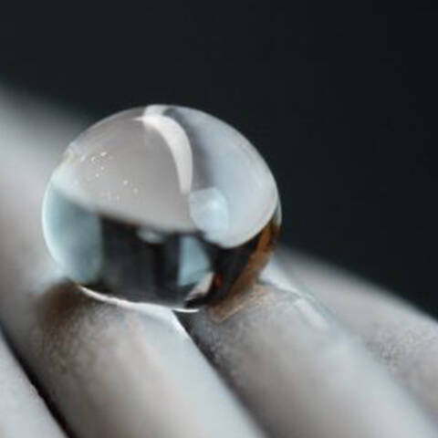 A close-up of a water droplet beaded on a twisted metal surface