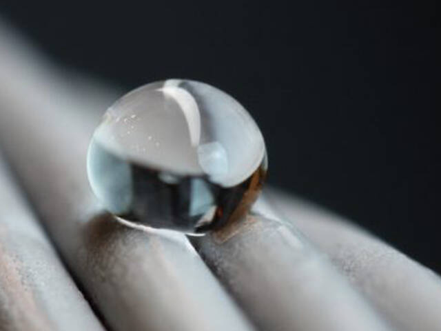 A close-up of a water droplet beaded on a twisted metal surface