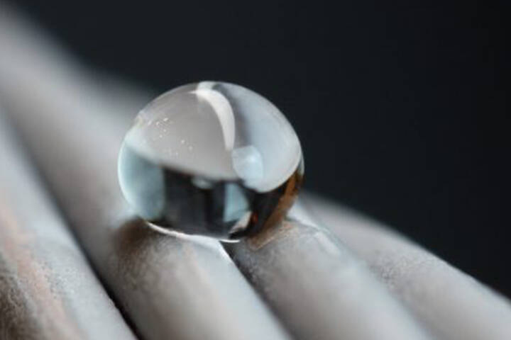 A close-up of a water droplet beaded on a twisted metal surface