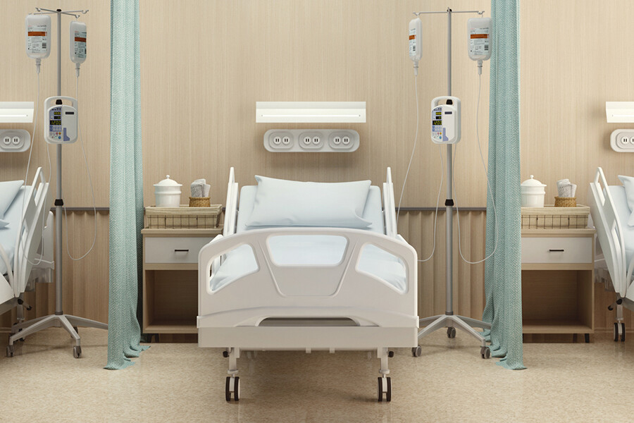 A hospital room with three symmetrical hospital beds and curtains separating them