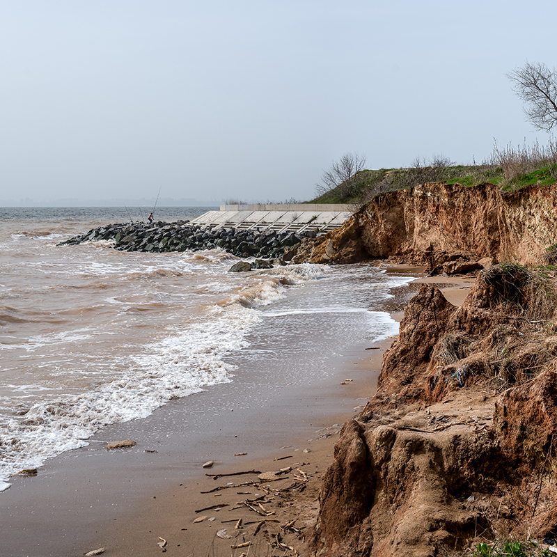 A beach with steep cliffs, and a wall preventing erosion