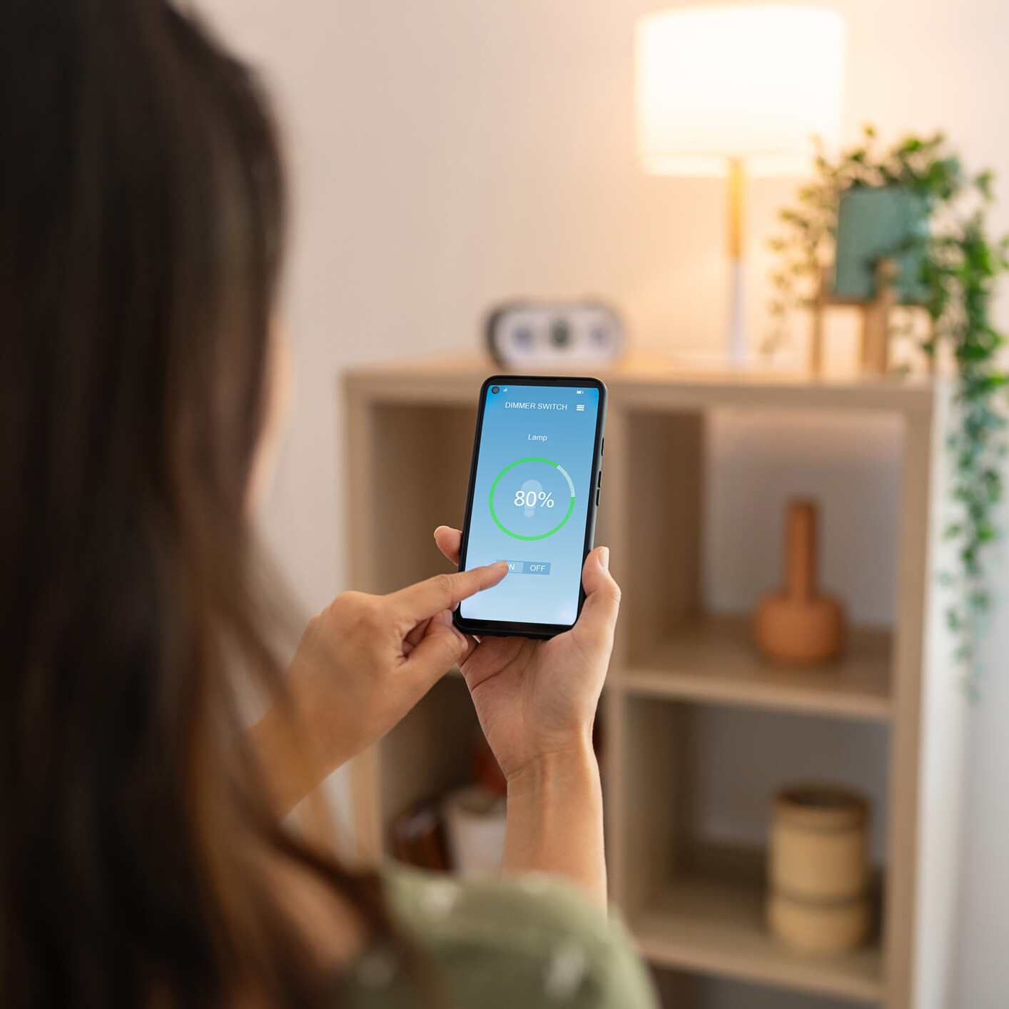 Woman controlling light with a smart phone at home.