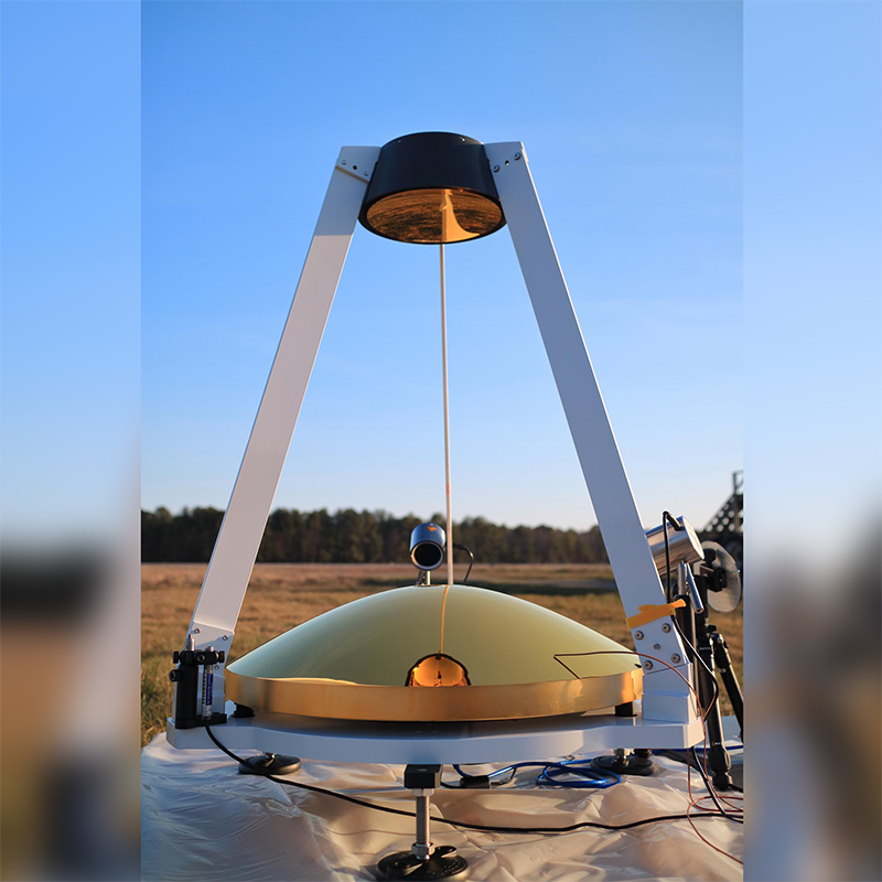 A MAMBA atmospheric sensor (a gold disc held by a triangular white frame) on a blue sky