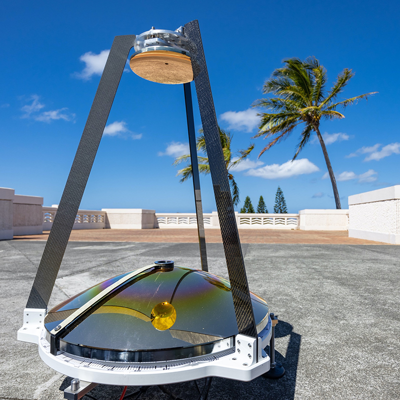 A MAMBA sensor on a concrete platform, with a low fence and palm trees in the background