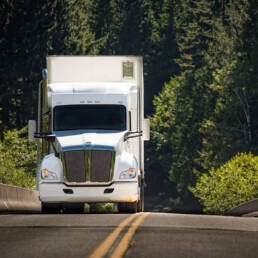 A semi truck driving on a concrete road