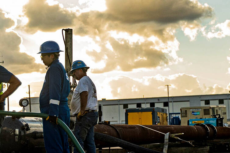 A group of workers examining a cable at a work site