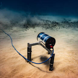 An ULTRA laser on the sea floor; a horizontal cylinder with a cable coming off the back
